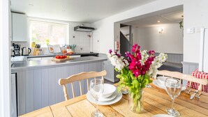 Une cuisine moderne avec des meubles gris, un îlot central et un coin repas comprenant une table et des chaises en bois.