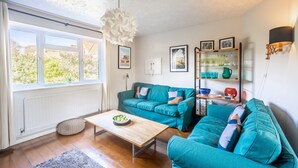 A living room with teal sofas, a wooden coffee table, and a white ceiling light fixture. - Fairstead Cottage, Holt, Norfolk (Holt)