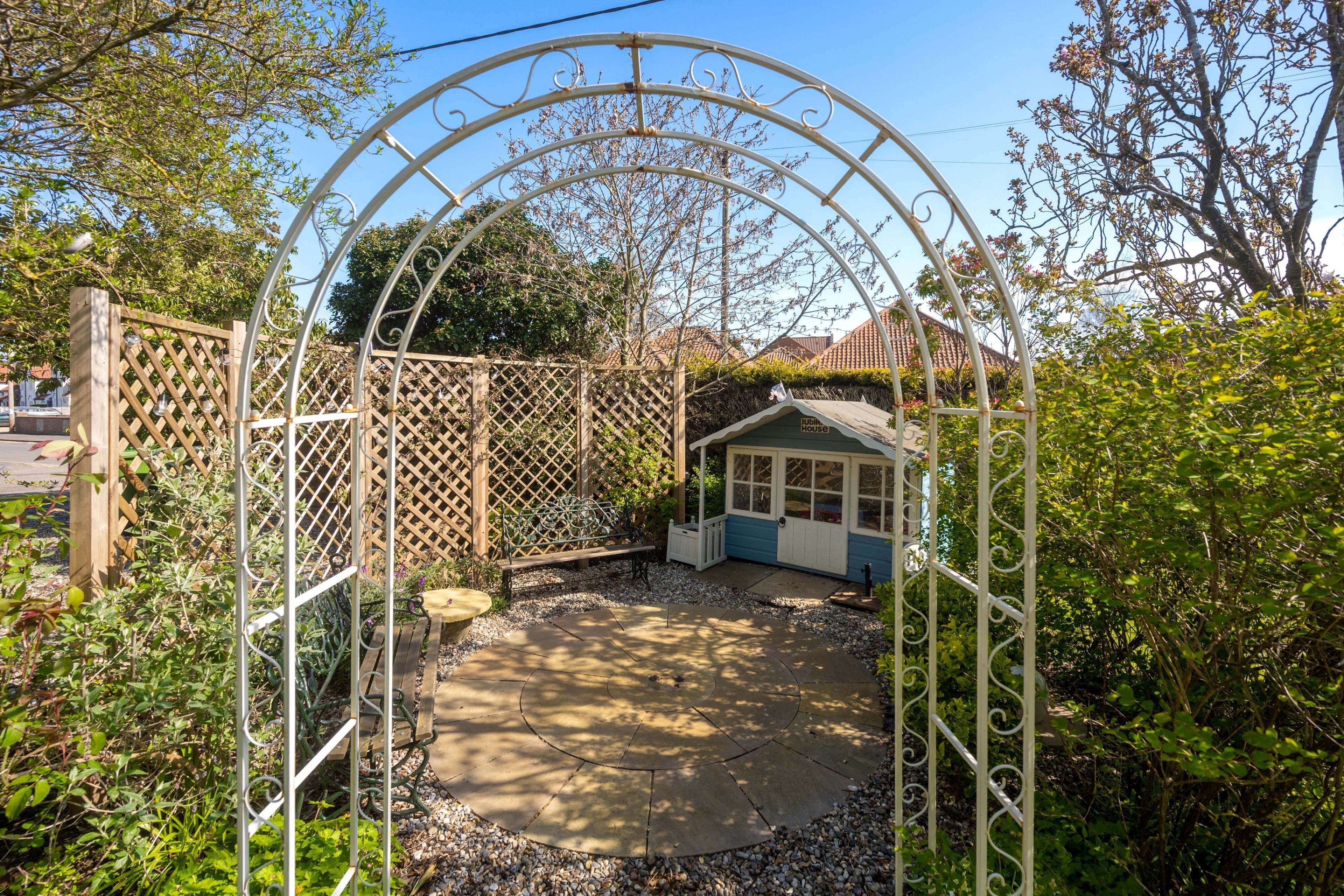 A garden with a gazebo, a small shed, and a wooden fence.