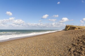 Ein Kiesstrand mit einer felsigen Klippe und Wellen.