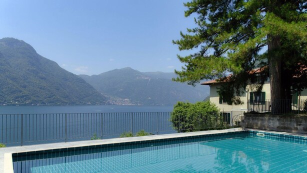 Piscina com vista para um lago e montanhas.