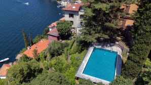 Piscina cercada por árvores e edifícios, com vista para a água.