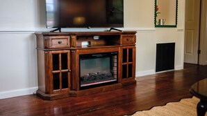A wooden entertainment center with a television above it and a fireplace below. - Adorable pet-friendly fenced home in Hampton! Welcome to Redheart Cottage <3 (Hampton)