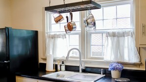 A kitchen with a black refrigerator, a stainless steel sink, and hanging pots. - Adorable pet-friendly fenced home in Hampton! Welcome to Redheart Cottage <3 (Hampton)