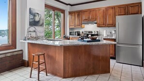 Una cocina con armarios de madera, encimera de granito, electrodomésticos de acero inoxidable y vistas al exterior.