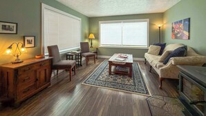 A living room with a wooden cabinet, two armchairs, a coffee table, and a sofa.