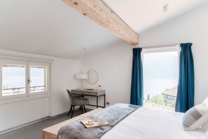 A bedroom with a bed, a desk, a chair, a window with curtains, and a view of the outside. - Luce -  MyHomeinComo (Acquaseria)