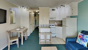 Un espace de vie compact comprenant un coin cuisine, un coin repas et un espace détente avec un canapé et une table basse.