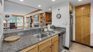 A modern kitchen with granite countertops, wooden cabinets, and a built-in dishwasher. - Spacious 4-Bedroom in Keystone-Walk to lifts! (Keystone)