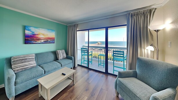 A living room with two sofas, a coffee table, and a view of the sea through large glass doors. - Casa Del Mar 350 - Front Facing | Coastal Condo w/ Private Balcony (Galveston)