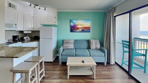 A compact living space with a kitchenette, a sofa, a coffee table, and a view of the balcony. - Casa Del Mar 350 - Front Facing | Coastal Condo w/ Private Balcony (Galveston)