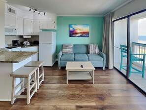 A compact living space with a kitchenette, a sofa, a coffee table, and a view of the balcony. - Casa Del Mar 350 - Front Facing | Coastal Condo w/ Private Balcony (Galveston)