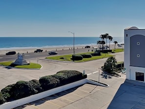 Ein Parkplatz mit Blick auf Strand und Meer, ein Denkmal sowie ein Gebäude mit einer Kuppel.