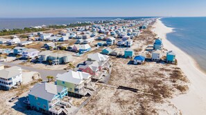 A coastal area with beachfront properties, some with multiple stories and balconies, and a sandy beach adjacent to the ocean. - Gulf-Front Duplex | Pet Friendly | Pools and Pier Access (Fort Morgan)