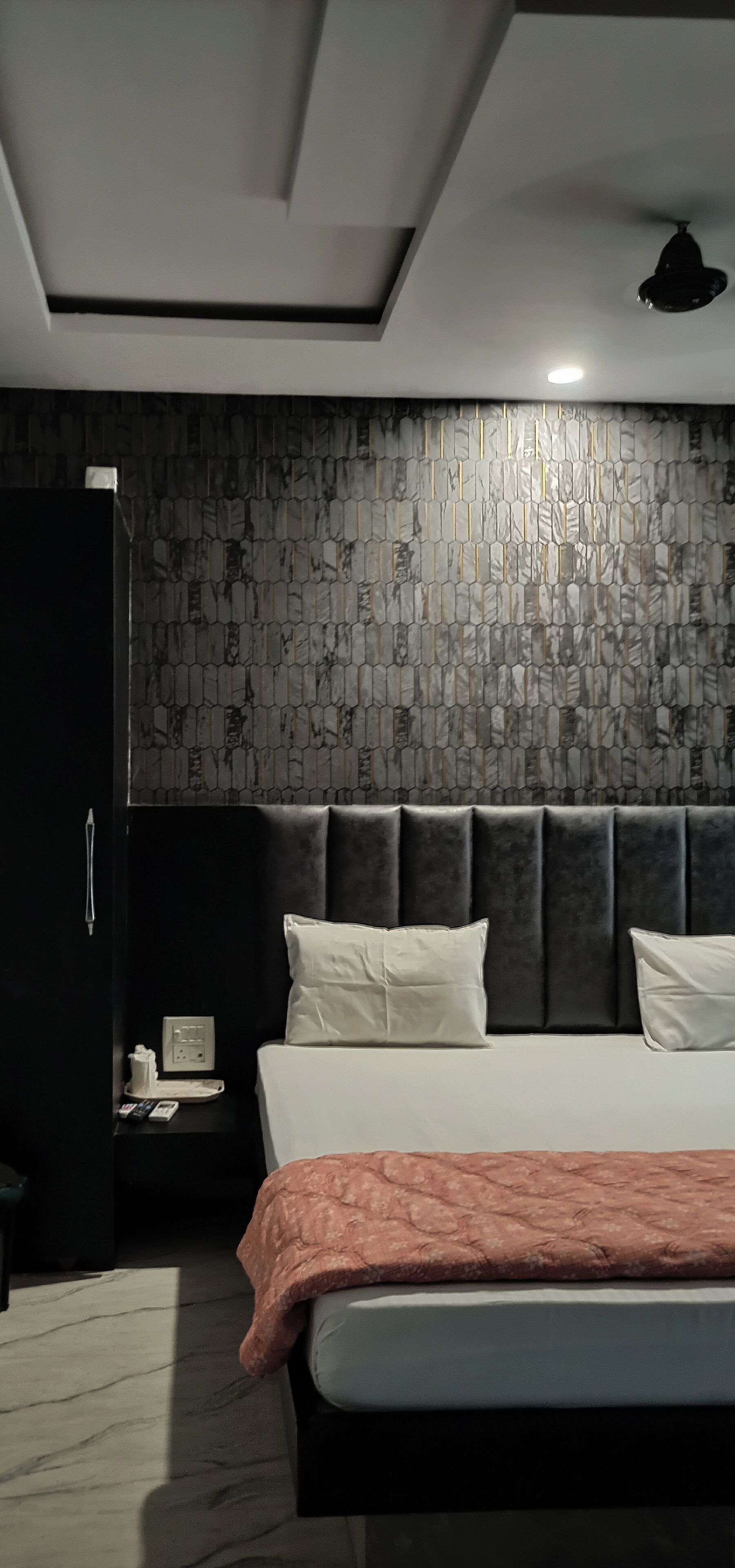 A modern bedroom with a bed, nightstand, and a dark wardrobe.