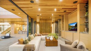 A spacious lobby with a wooden ceiling, a large sofa, a coffee table, and a TV on the wall. - Oak Pass Manor: Indoor-outdoor Luxury With Pool, Sauna & Panoramic Views (Beverly Hills)
