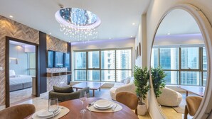 Ein modernes Hotelzimmer mit Essbereich, großen Fenstern, einem Spiegel und einer Chandelier.