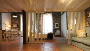 Un salon avec un canapé, un coin repas avec une table et des chaises, et une cuisine équipée d’une cuisinière.