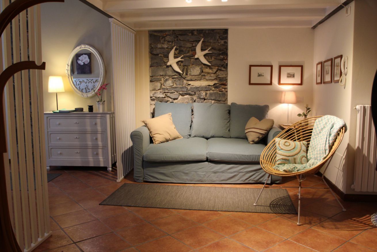 A cozy living room with a sofa, a chair, a fireplace, and a stone wall.