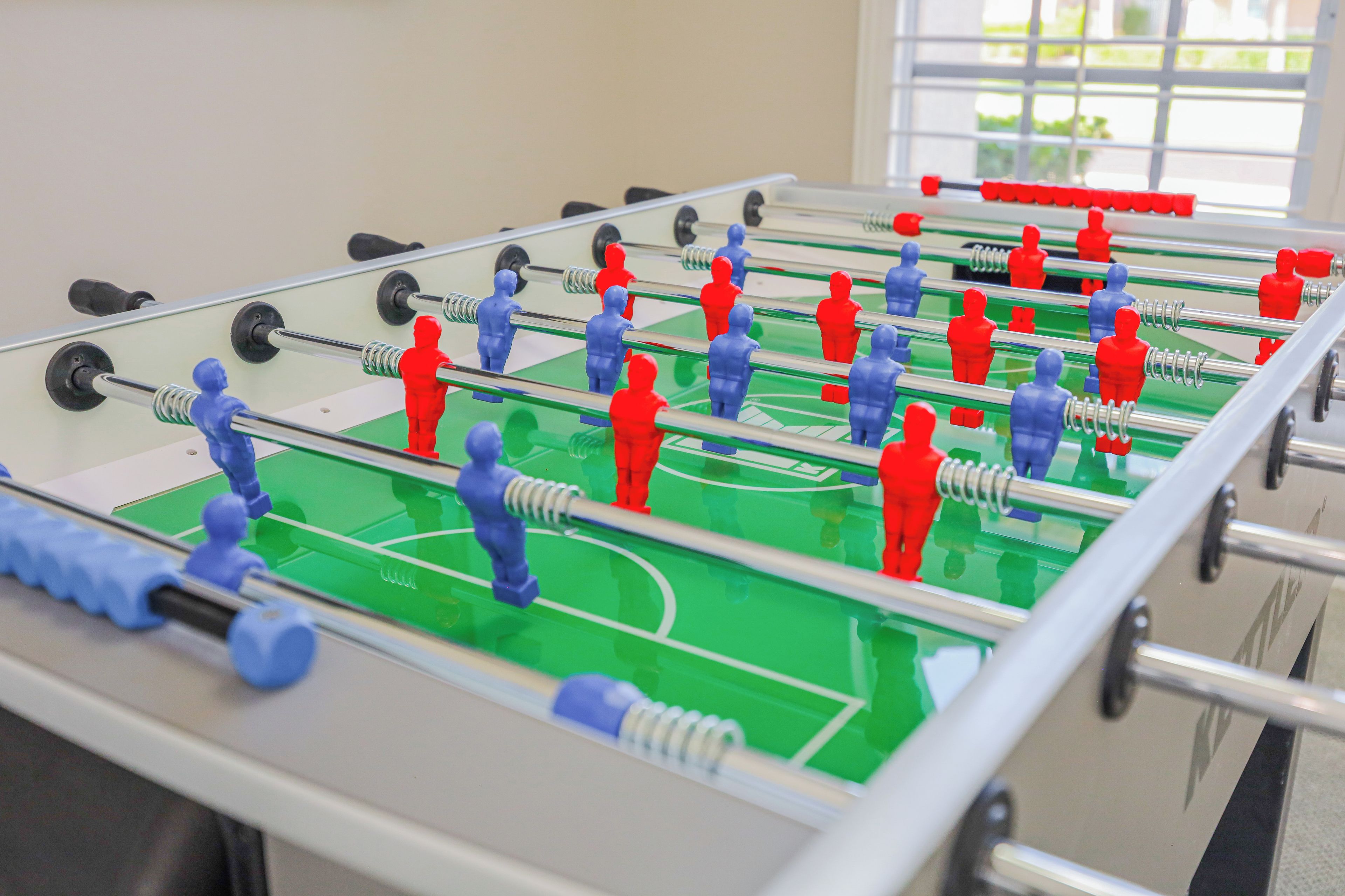 A foosball table with red and blue figures, set against a green playing field.
