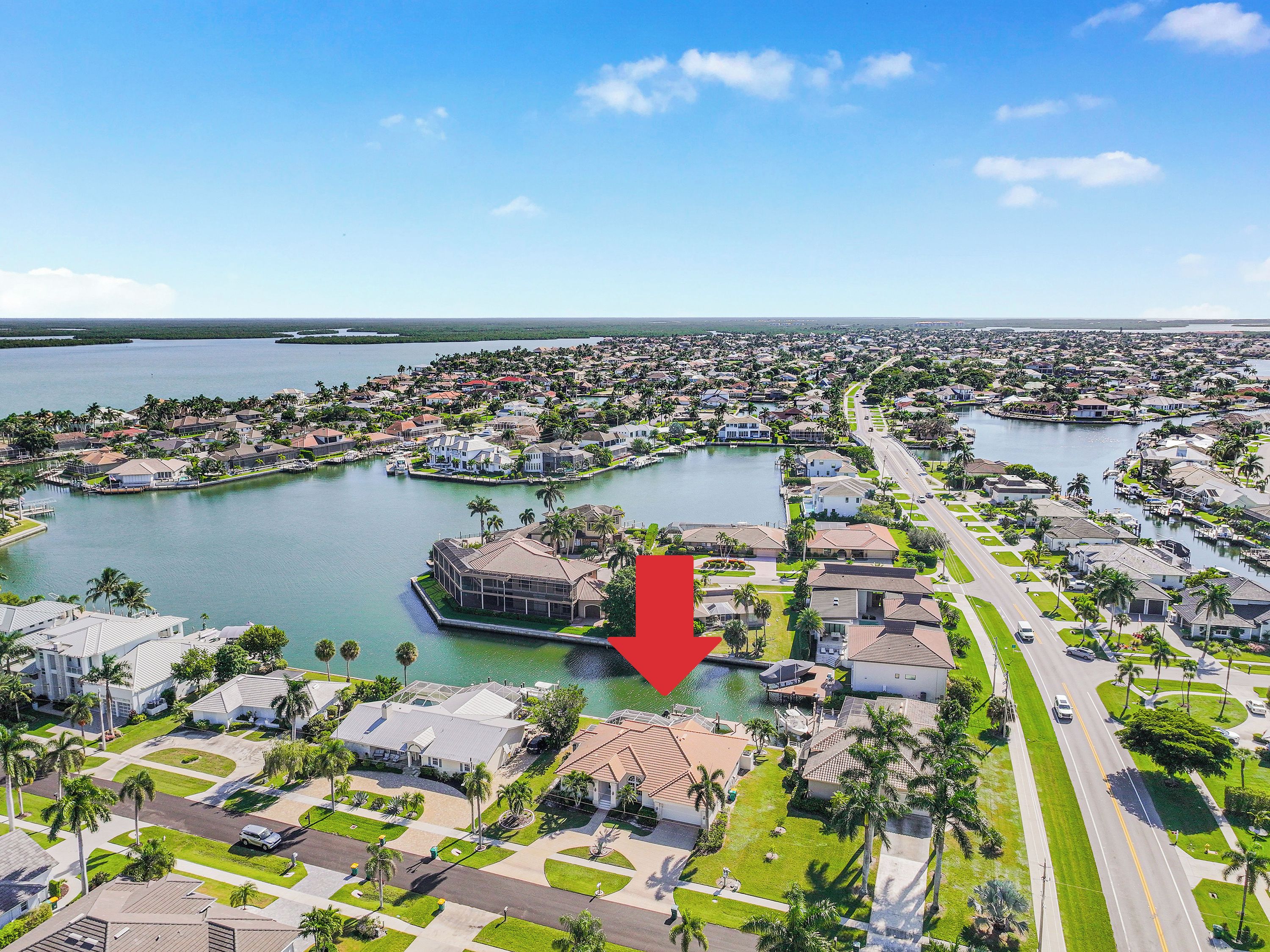 An aerial view of a residential area with houses, a marina, and a large body of water.