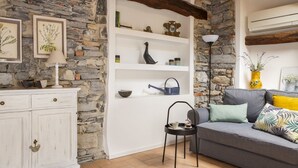 Een stenen muur, witte planken, een grijze bank, een witte kast en een vloerlamp.