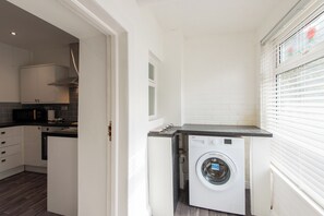 A compact kitchen with white cabinets, a built-in microwave, and a washing machine. - Toast Stays - The Merrington Fold (Kirk Merrington)