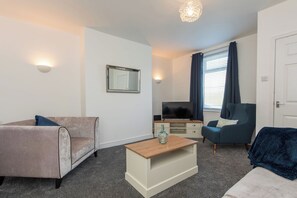 A modern living room with a sofa, a coffee table, a TV, and a chair. - Toast Stays - The Merrington Fold (Kirk Merrington)