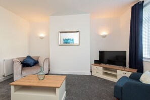 A modern living room with a sofa, a coffee table, a TV, and a framed artwork on the wall. - Toast Stays - The Merrington Fold (Kirk Merrington)