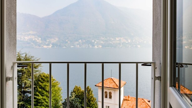 A balcony with a metal railing, overlooking a lake with a mountain in the background. - Madonnina Loft - MyHomeinComo (Moltrasio)