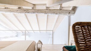 A bedroom with a wooden ceiling, a bed, a wicker chair, and a lantern. - Madonnina Loft - MyHomeinComo (Moltrasio)