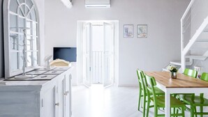 A kitchen with white cabinets, a wooden ceiling, and a dining area with green chairs. - Madonnina Loft - MyHomeinComo (Moltrasio)
