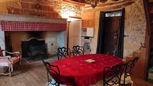 Un comedor rústico con una mesa y sillas de madera, chimenea y pared de piedra.
