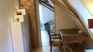 Dormitorio tipo loft con vigas de madera a la vista, pared de piedra, escritorio de madera y una silla.