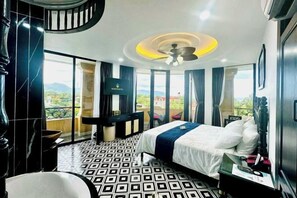 A hotel room with a bed, a desk, a chair, a TV, and a balcony with a view. - Nereus Hotel (Con Dao Island)