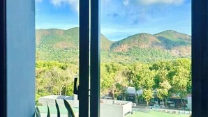 A view through a window with a mountain landscape, including greenery and a few buildings. - Nereus Hotel (Con Dao Island)