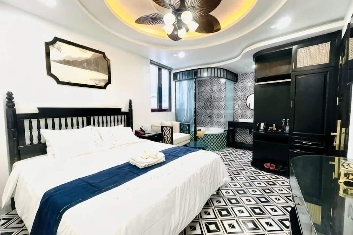 A bedroom with a bed, a desk, a wardrobe, and a ceiling fan.
