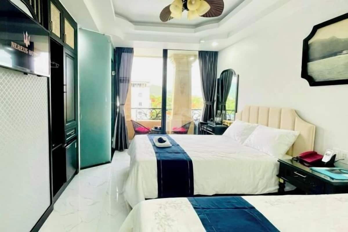 A hotel room with a bed, a desk, a chair, a wardrobe, and a balcony with a view.