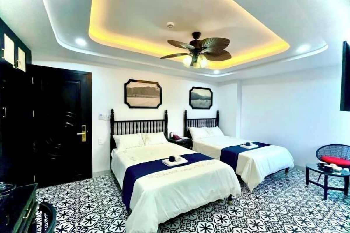 A hotel room with two beds, a ceiling fan, and a patterned floor.