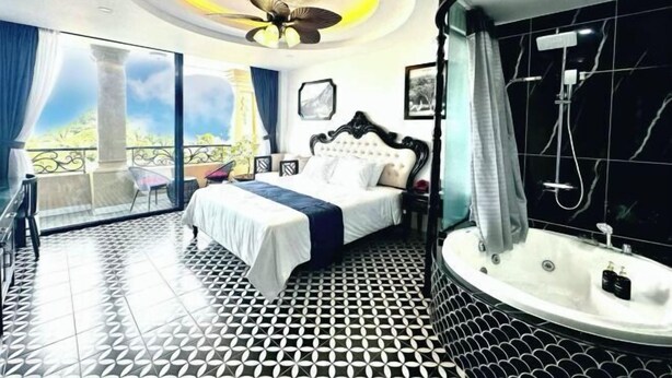 A bedroom with a bed, a bathroom with a bathtub, and a balcony with a view. - Nereus Hotel (Con Dao Island)