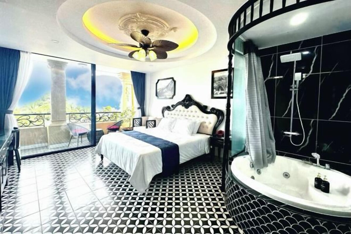 A bedroom with a bed, a bathroom with a bathtub, and a balcony with a view.