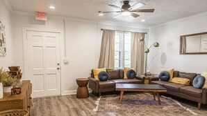 Una sala de estar con un sofá de cuero marrón, una mesa de centro de madera y un tapete estampado.