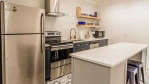 Una cocina moderna con electrodomésticos de acero inoxidable, una isla central y un salpicadero decorativo.