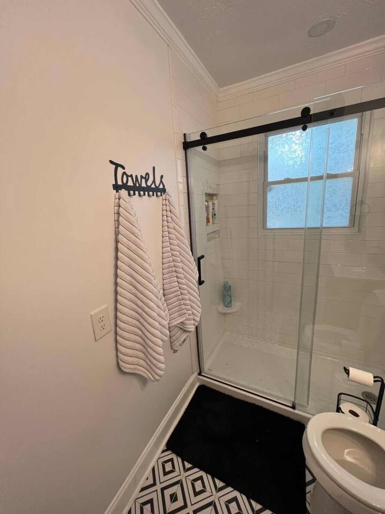 Ein Badezimmer mit Dusche, Toilette und Handtuchhalter mit Handtüchern.