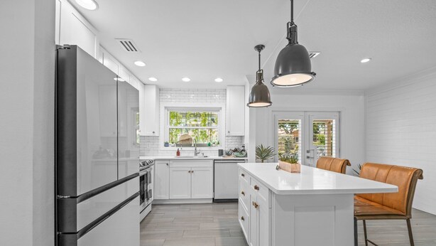 A modern kitchen with white cabinetry, a central island, and pendant lighting. - The Waterfront Family Oasis- Pool, Dock & Relaxing Backyard (Ellenton)