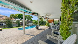 A covered outdoor area with a pool, seating, and a ceiling fan. - The Waterfront Family Oasis- Pool, Dock & Relaxing Backyard (Ellenton)