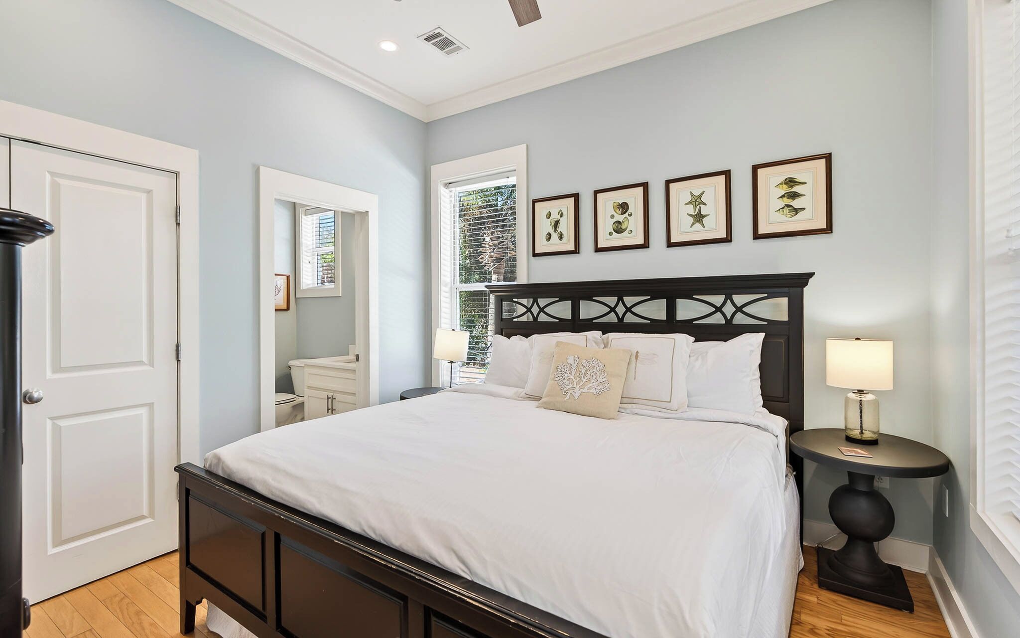 A bedroom with a bed, bedside tables, a window, and framed artwork on the wall.