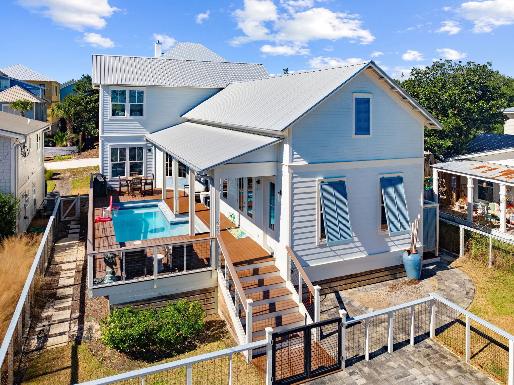 A two-story house with a swimming pool, a covered patio, and a fenced deck area.