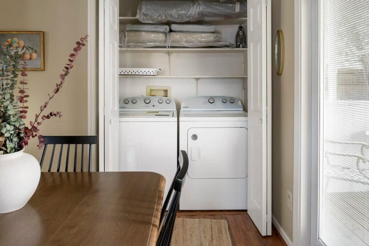 A compact laundry room with a washing machine and dryer, a small table, and a chair.