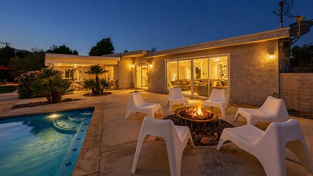 Ein modernes Haus mit Swimmingpool, Sitzgelegenheit im Freien und einer Feuerstelle.
